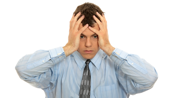 a man in a shirt and tie covers his face with his hands